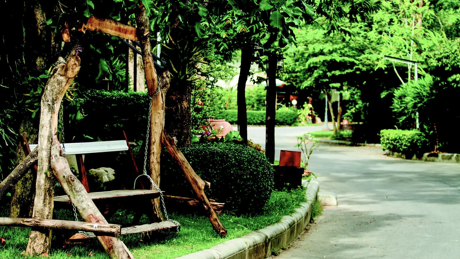 Wooden swing seating beside a shaded garden path at Baantip