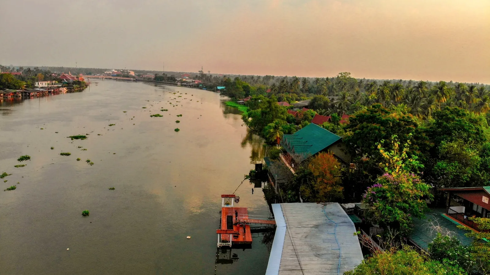 River view from above Baantip, with trees and roofs in the foreground and neighbouring buildings across the water