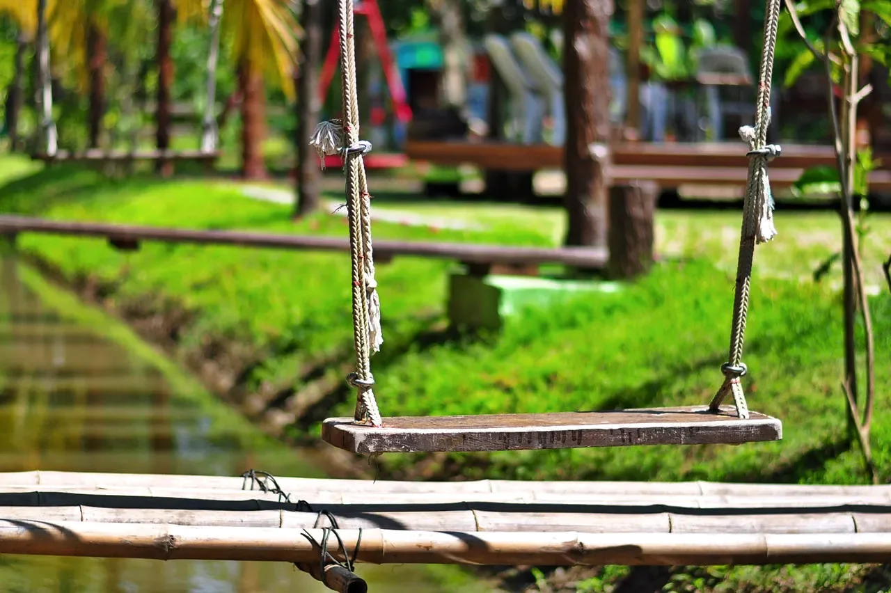Wooden swing above a garden waterway at Baantip