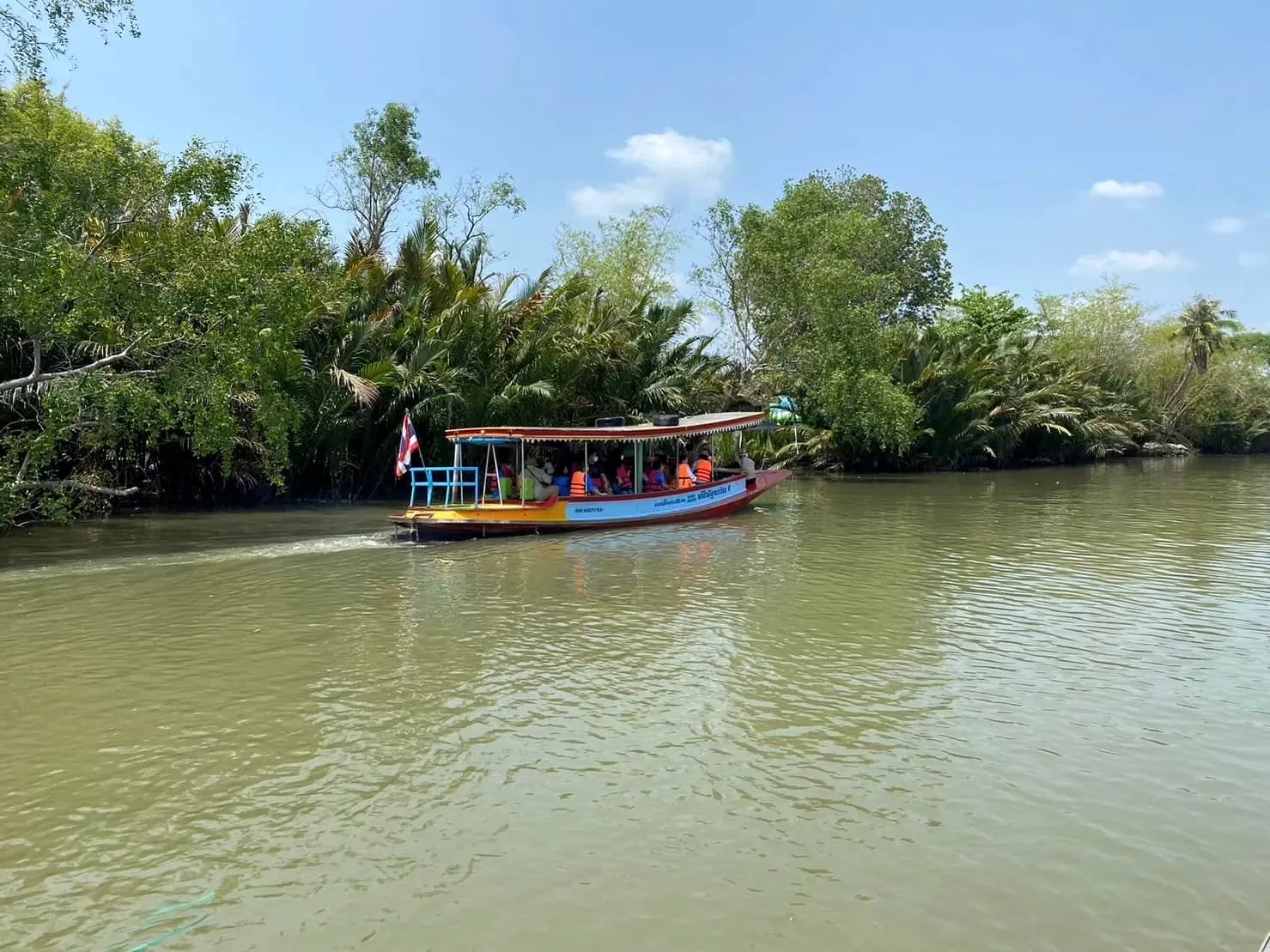 A passenger boat passing a tree-lined riverbank